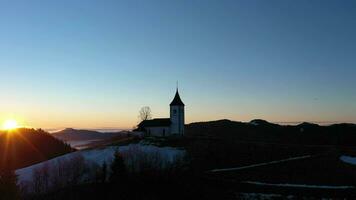 Igreja do st. primoz e Felicijan às nascer do sol acima a nuvens. juliano Alpes. jamnik, Eslovénia, Europa. aéreo visualizar. órbita video
