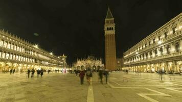 VENICE, ITALY - FEBRUARY 19, 2022 Illuminated St Marks Square at Night. St Marks Campanile and Tourists. Time Lapse video