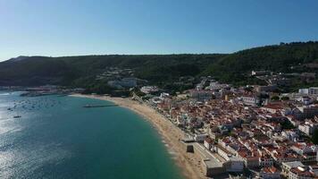 sesimbra stad- Aan zonnig dag. zanderig strand en atlantic oceaan. groen heuvels. Portugal. antenne visie. dar vliegt achteruit video