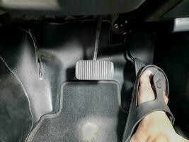 Close up images of man driving car by pushing accelerator and brake pedal with right foot with slippers photo