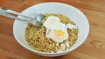 Boiled instant noodles. A bowl of instant noodle with egg in the wooden table. photo