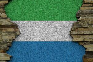 Sierra Leone flag depicted in paint colors on old stone wall closeup. Textured banner on rock wall background photo