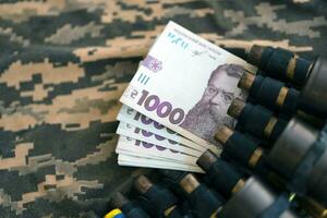 Ukrainian army machine gun belt shells and bunch of hryvnia bills on military uniform. Payments to soldiers of the Ukrainian army, salaries to the military photo
