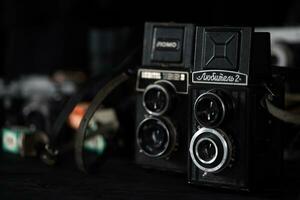 KHARKOV, UKRAINE - APRIL 27, 2021 Lubitel 166b and 2 Film photo camera and another old retro photo equipment on black wooden table in photographer darkroom. Photographic gear from soviet union