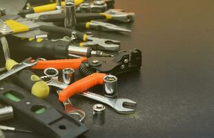 Handyman tool kit on black wooden table. Many wrenches and screwdrivers, pilers and other tools for any types of repair or construction works. Repairman tools photo