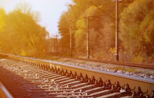Autumn industrial landscape. Railway receding into the distance among green and yellow autumn trees photo