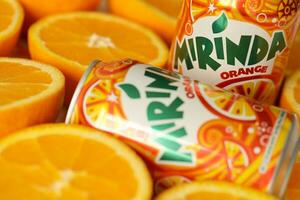 KYIV, UKRAINE - JULY 7, 2023 Mirinda orange drink with many oranges on colorful background photo