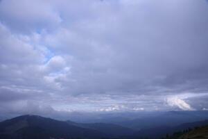 Morning view from the Dragobrat mountain peaks in Carpathian mountains, Ukraine. Cloudy and foggy landscape around Drahobrat Peaks photo