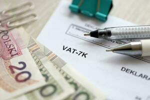 Declaration for tax on goods and services VAT-7K form on accountant table with pen and polish zloty money bills photo