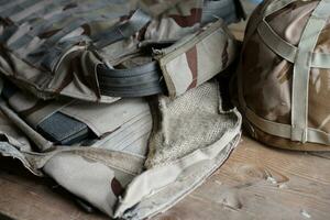 A military helmet of a Ukrainian soldier with a heavy bulletproof vest on wooden table in checkpoint dugout photo