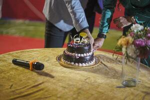 Men's hand cuts a large cake with a knife photo