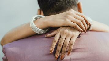 A closeup of a woman's hands with a marriage ring linked on a man's neck photo