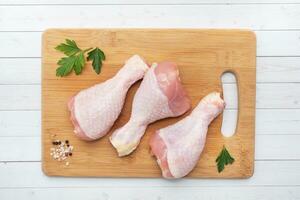 Raw chicken drumsticks with parsley and spices on a wooden cutting Board. top view copy space photo
