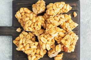 Peanuts in sugar glazed, oriental sweetness of brittle. Kozinaks are broken into pieces on a wooden Board, copy space. top view photo