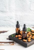 almendra esencial petróleo en oscuro vaso burbujas y Fresco almendra nueces. aromaterapia petróleo natural orgánico cosmético. foto