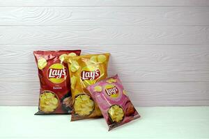 KHARKOV, UKRAINE - JANUARY 3, 2021 Various flavoured of lay's potato chips on wooden background. Lay's has been owned by PepsiCo through Frito-Lay in 1965 photo