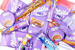 kharkov, ucrania - 2 de julio de 2021 productos de chocolate milka con diseño de envoltura de color lila clásico en mesa blanca foto