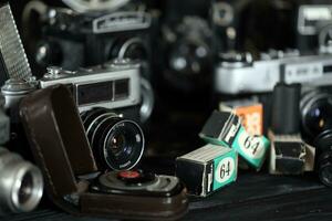 KHARKOV, UKRAINE - APRIL 27, 2021 Film photo cameras and another old retro photo equipment on black wooden table in photographer darkroom. Photographic gear from soviet union