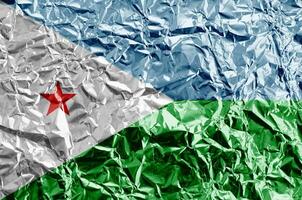Djibouti flag depicted in paint colors on shiny crumpled aluminium foil closeup. Textured banner on rough background photo