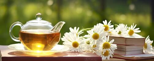 Chamomile flowers, books, a glass teapot, and a cup of herbal tea on a table closeup. Generative AI photo