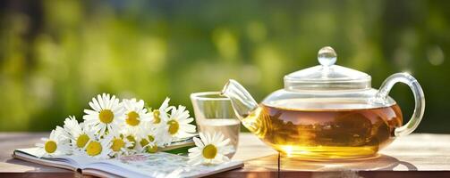 Chamomile flowers, books, a glass teapot, and a cup of herbal tea on a table closeup. Generative AI photo