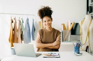 Calm curly brunette dark skinned woman on desk of fashion designer and holds tablet photo