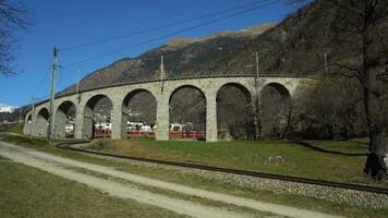 brusio, Zwitserland - februari 23, 2022 trein Aan Brusio spiraal viaduct in Zwitserland Aan zonnig dag. Bernina spoorweg. Zwitsers Alpen video