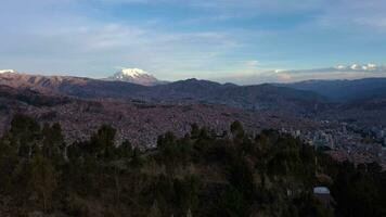 la paz stadsbild och illimani berg. antenn se. bolivia. gyllene timme. Drönare flugor fram, luta ner. bred skott. upprättande skott video