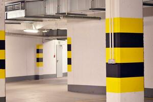 Typical underground car parking garage in a modern apartment house. Interior pillars painted yellow. photo