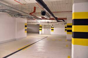 Typical underground car parking garage in a modern apartment house. Interior pillars painted yellow. photo