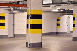 Typical underground car parking garage in a modern apartment house. Interior pillars painted yellow. photo