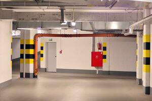 Typical underground car parking garage in a modern apartment house. Interior pillars painted yellow. photo