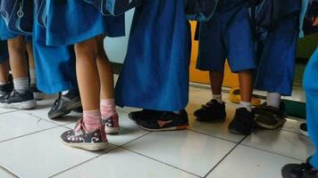 magelang, Indonesien.11 06 2023.a grupp av glad indonesiska lantlig skola barn eller barn bär uniformer och ryggsäckar lämnar eller löpning ut av de klassrum efter skola är över, video