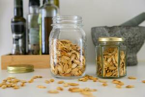 Two jars with pumpkin seeds on a kitchen table photo