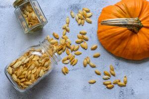 Two jars with pumpkin seeds on a rustic table photo