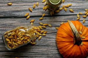 Two jars with pumpkin seeds on a rustic table photo