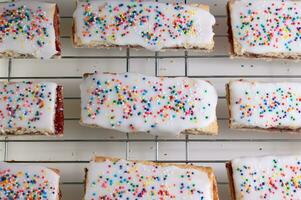 Icing covered pastries with sprinkles seen from above. photo