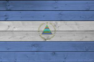 Nicaragua bandera representado en brillante pintar colores en antiguo de madera pared. texturizado bandera en áspero antecedentes foto