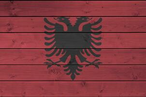 Albania bandera representado en brillante pintar colores en antiguo de madera pared. texturizado bandera en áspero antecedentes foto