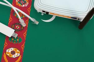 Turkmenistan flag depicted on table with internet rj45 cable, wireless usb wifi adapter and router. Internet connection concept photo