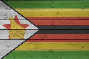 Zimbabue bandera representado en brillante pintar colores en antiguo de madera pared. texturizado bandera en áspero antecedentes foto