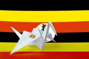 Uganda flag depicted on paper origami crane wing. Handmade arts concept photo