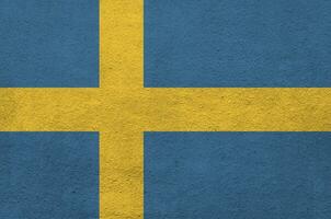 Sweden flag depicted in bright paint colors on old relief plastering wall. Textured banner on rough background photo