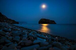 Starry night with a full moon over sea with rock in front. Cape Fiolent, Jasper beach rock of the holy phenomenon with a cross on the background of the moon photo