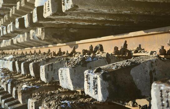 A lot of old rails and sleepers are stacked in a railway warehouse in winter. The concept of renewing a worn-out railway track photo
