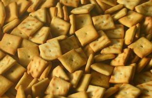 Background texture of small edible squares baked from dough and sprinkled with salt. A lot of salt cracker photo