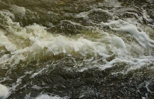 Waves of water of the river and the sea meet each other during high tide and low tide. Deep blue stormy sea water surface with white foam and waves pattern, background photo