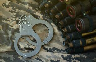 Ukrainian army machine gun belt shells and handcuffs on military uniform. Concept of bribery and war crimes photo