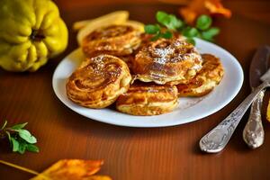 Cooked fried round pancakes with quince filling on a wooden table photo