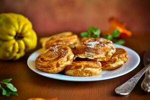 Cooked fried round pancakes with quince filling on a wooden table photo